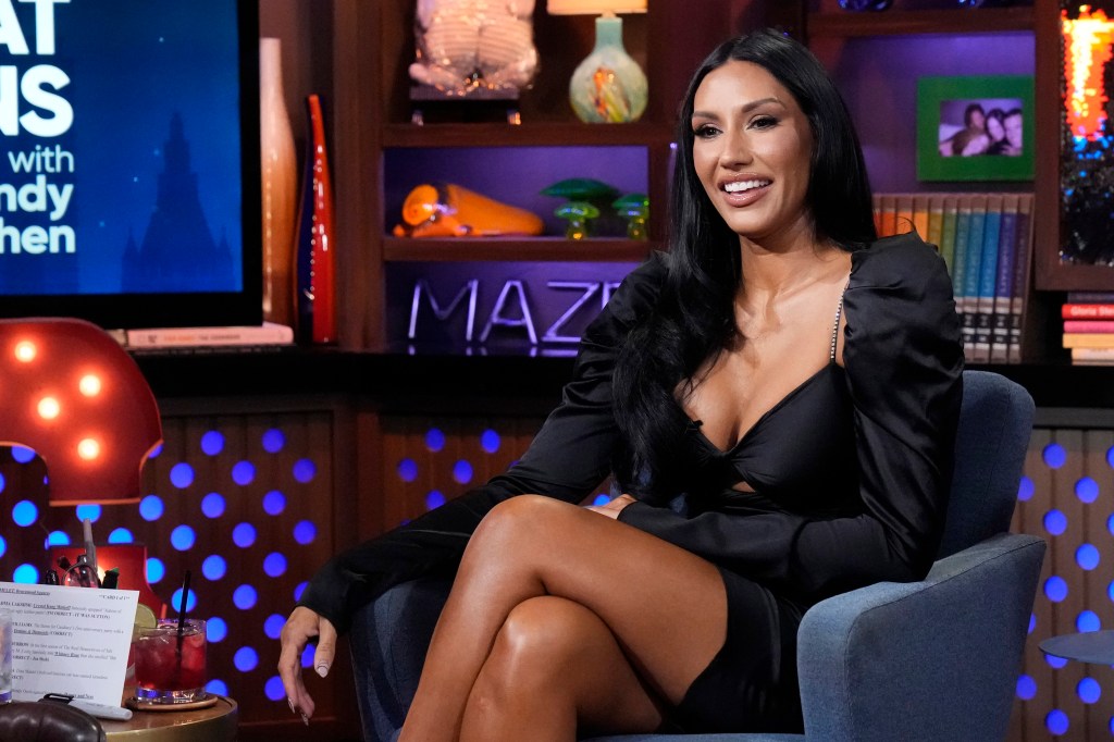 Monica Garcia in a black dress sitting with her legs crossed on Watch What Happens Live