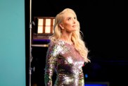 Erika Jayne in a silver dress, looking up at a stage light