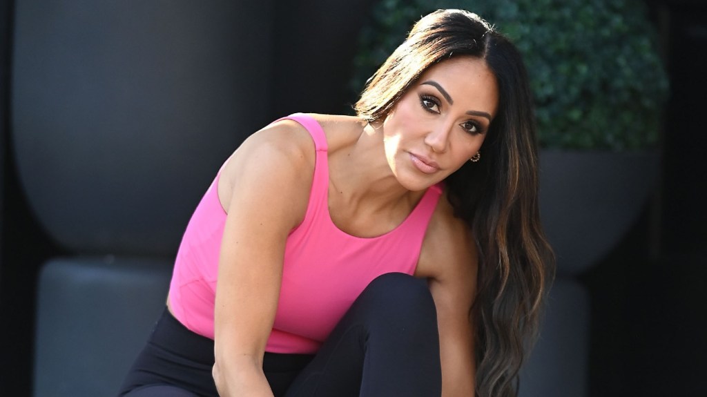 Melissa Gorga in a pink yoga outfit tying her shoes