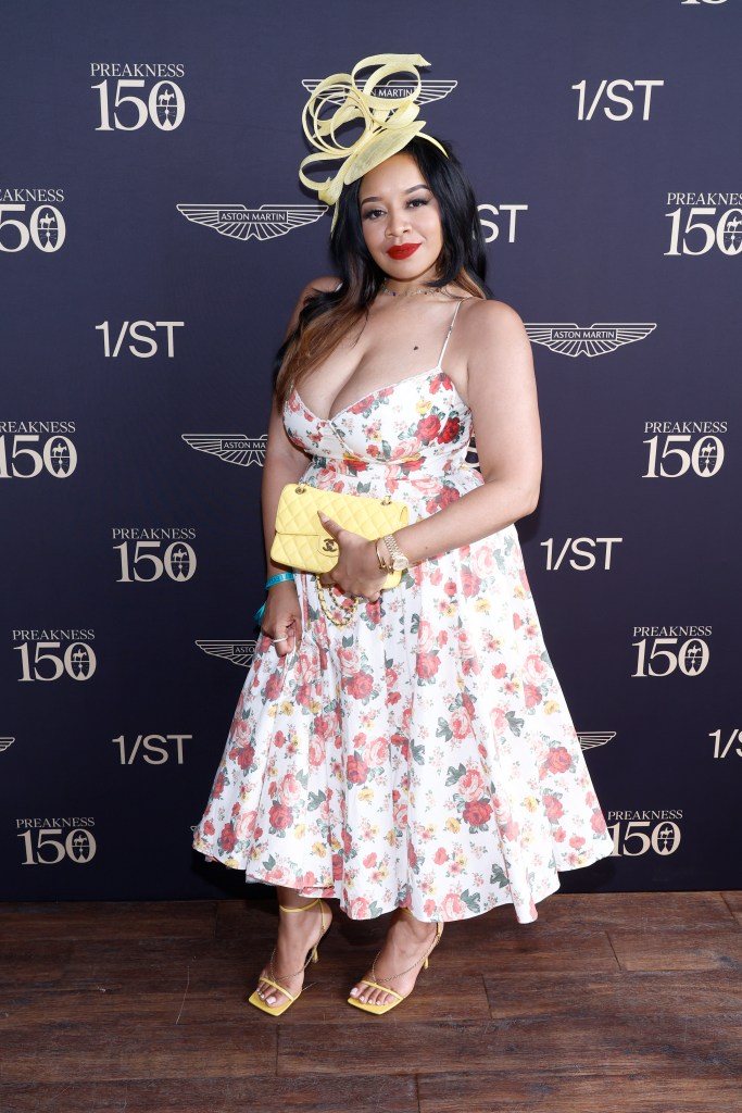 Angel Massie at Preakness wearing a floral dress and yellow fascinator