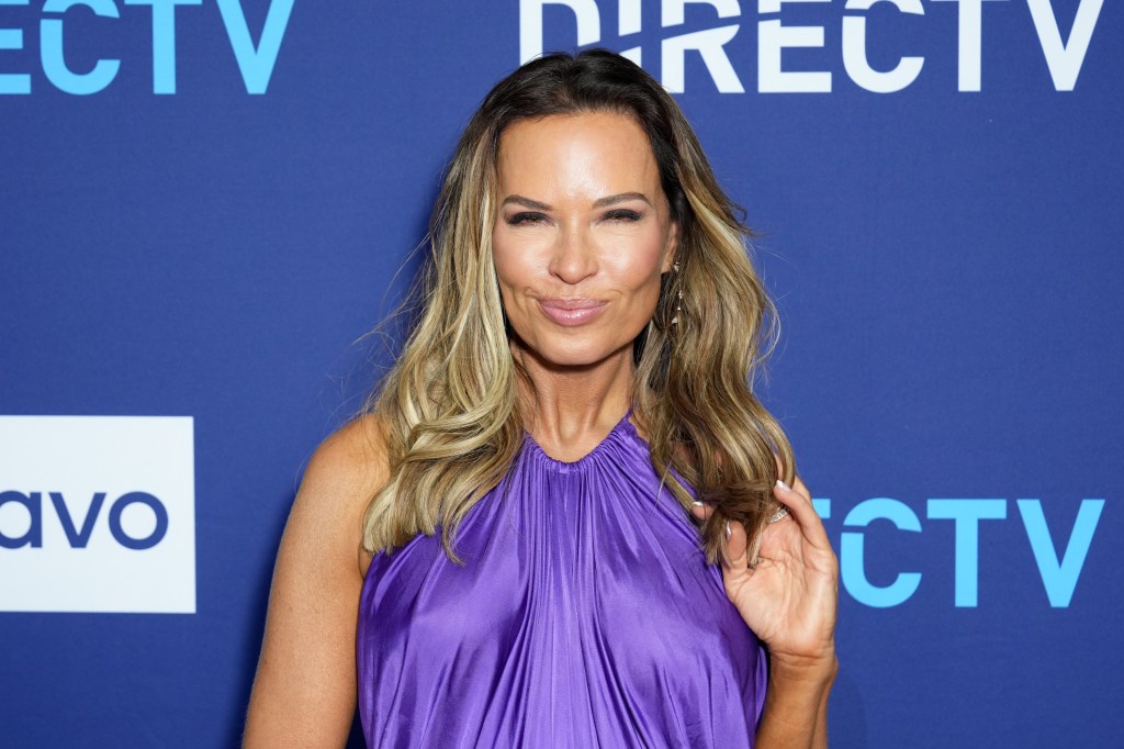Britani Bateman in a purple dress in front of a blue backdrop