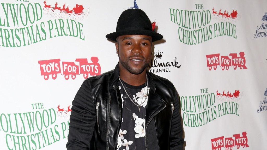 Joshua Allen posing at the Hollywood Christmas Parade wearing a black jacket and black hat