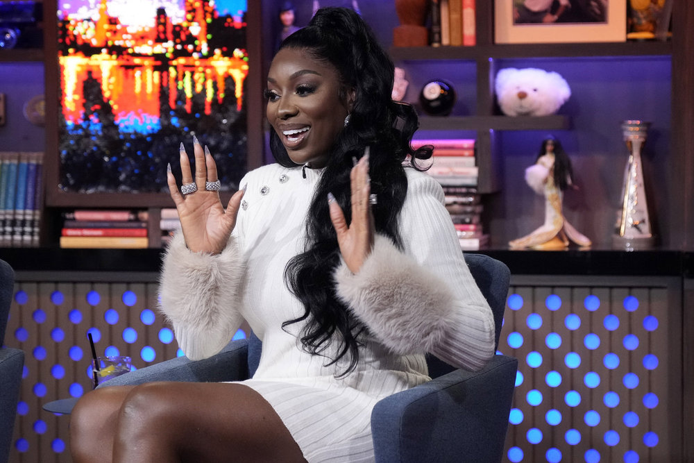 Wendy Osefo raising her hands and wearing a white dress on Watch What Happens Live