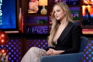 Jennifer Lawrence in a black blazer, sitting with her legs crossed on Watch What Happens Live