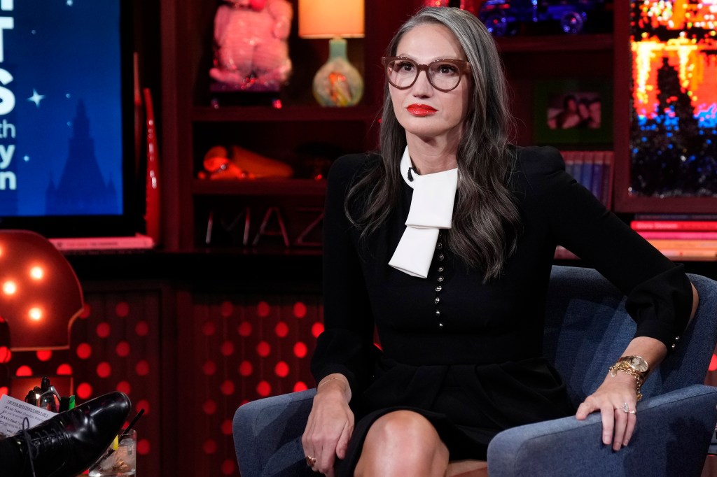 Jenna Lyons in a black dress on Watch What Happens Live, sitting up in her seat