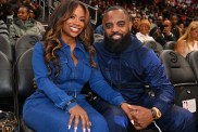 Kandi Burruss and Todd Tucker wearing blue jumpsuits and sitting courtside at an Atlanta Hawks game