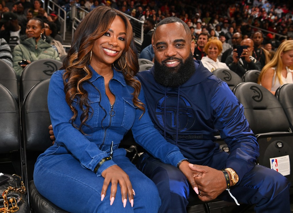 Kandi Burruss and Todd Tucker wearing blue jumpsuits and sitting courtside at an Atlanta Hawks game