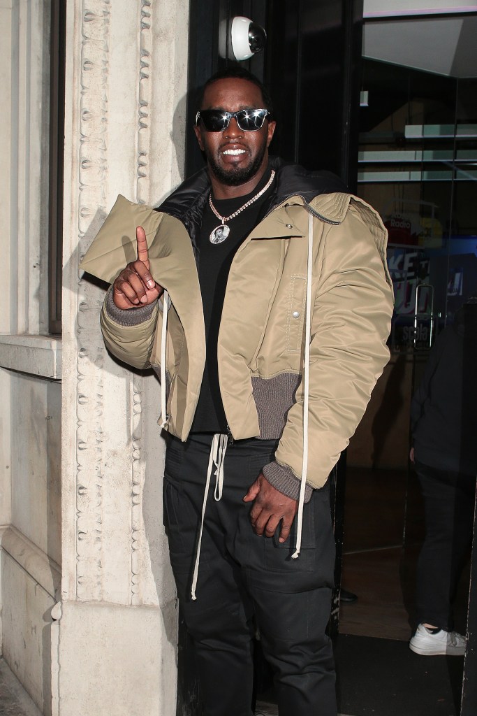 Sean Diddy Combs in a brown coat, holding up his index finger
