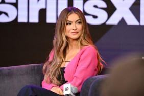 Chrishell Stause in a pink sweater at SiriusXM studios, holding a microphone in her hand