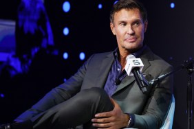Jeff Lewis in a grey suit, sitting with his legs crossed on stage at a SiriusXM event