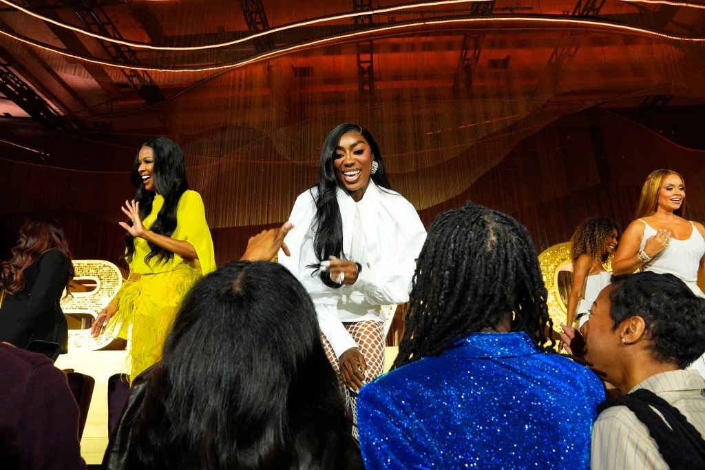 Wendy Osefo dressed in white, greeting fans while on stage at BravoCon 2025