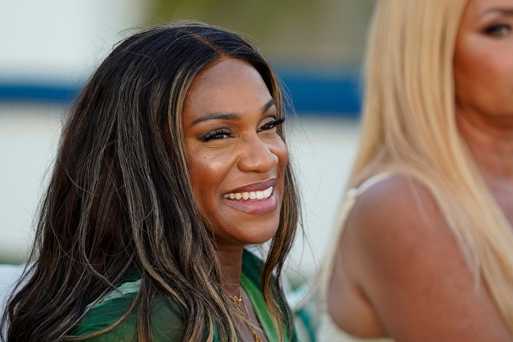 Tia Glover smiling and sitting next to Gizelle Bryant