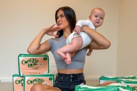 Gael Cameron holding up her baby and sitting amongst a bunch of diaper boxes