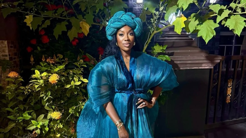 Wendy Osefo in a blue Nigerian outfit posing with her hand on her hip
