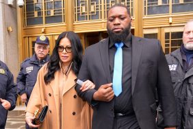 Jen Shah in a brown coat walking arm in arm with a security guard, leaving a courthouse