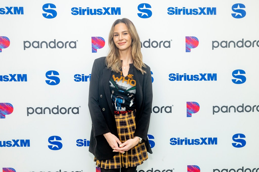 Meghan King in a plaid skirt and black blazer, posing at SiriusXM studios