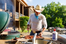 Steven McBee Sr hovering over a BBQ grill with a tray full of meat