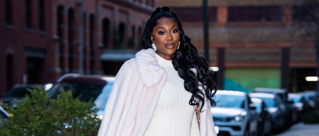 Wendy Osefo in a white coat walking through traffic