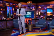 Andy Cohen in a light blue suit, standing inside of the Watch What Happens Live studio