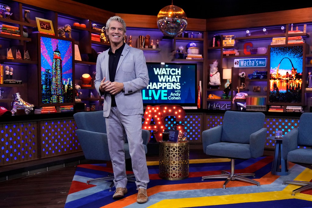 Andy Cohen in a light blue suit, standing inside of the Watch What Happens Live studio