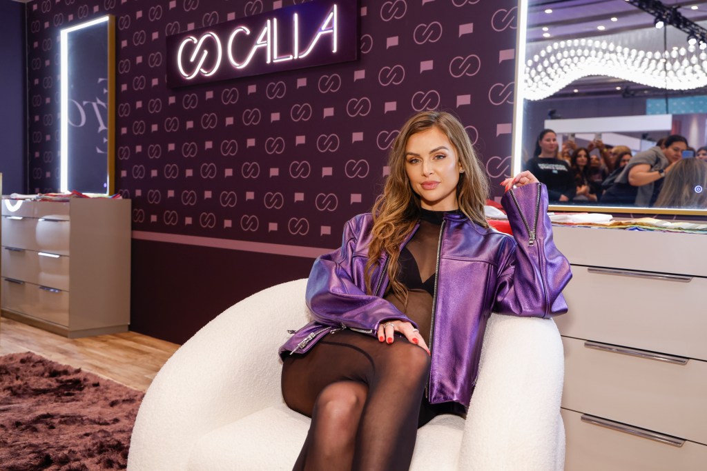 Lala Kent in a purple jacket sitting in a white chair at BravoCon 2025