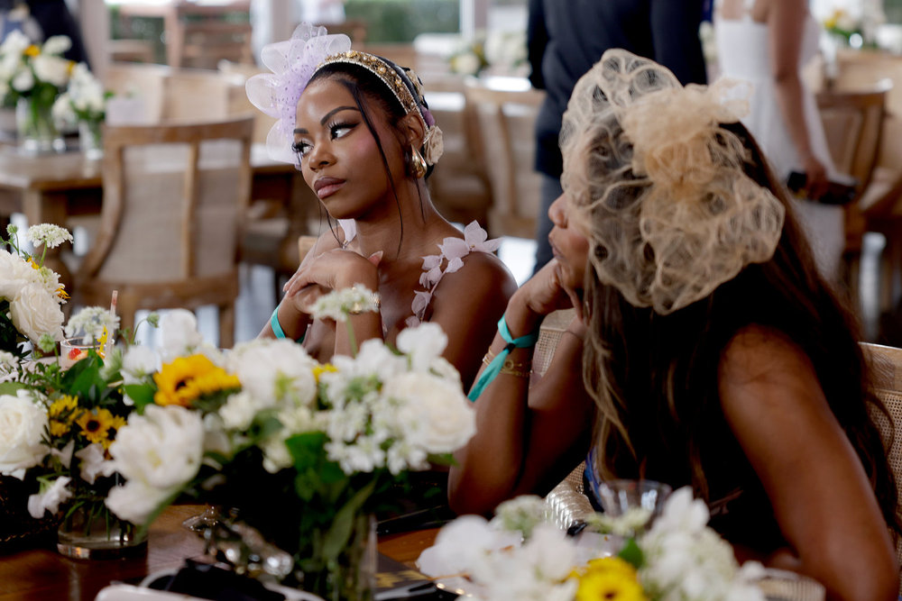 Keiarna Stewart and Tia Glover sitting at a table with flowers while attending Preakness 