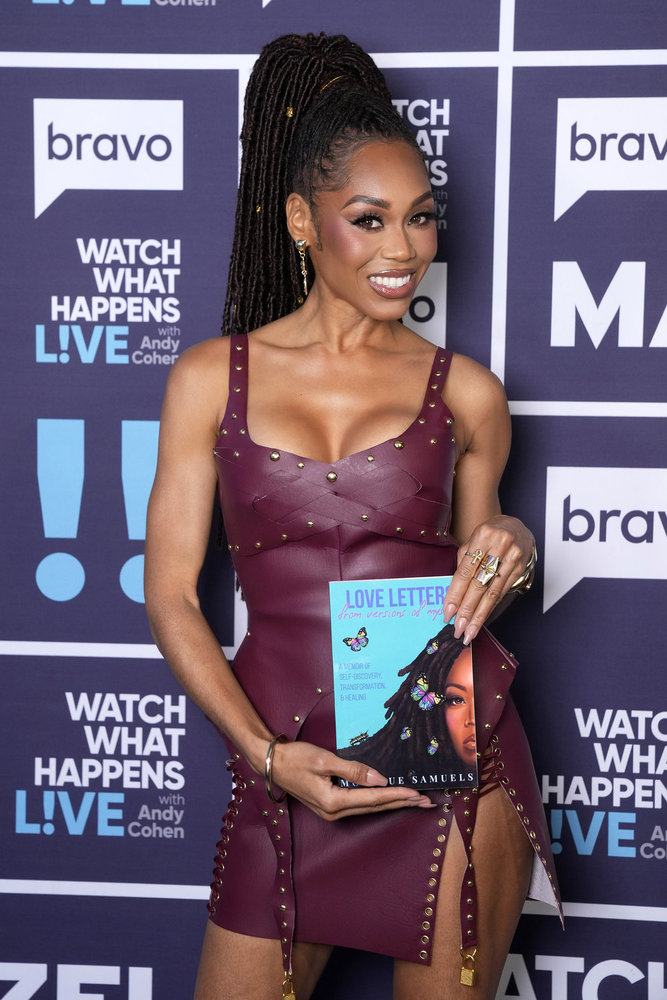 Monique Samuels in a burgundy dress, posing with her book backstage at Watch What Happens Live