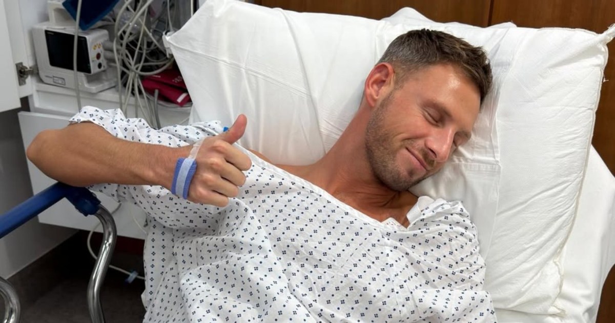 Fraser Olender laying in a hospital bed giving a thumbs-up to the camera