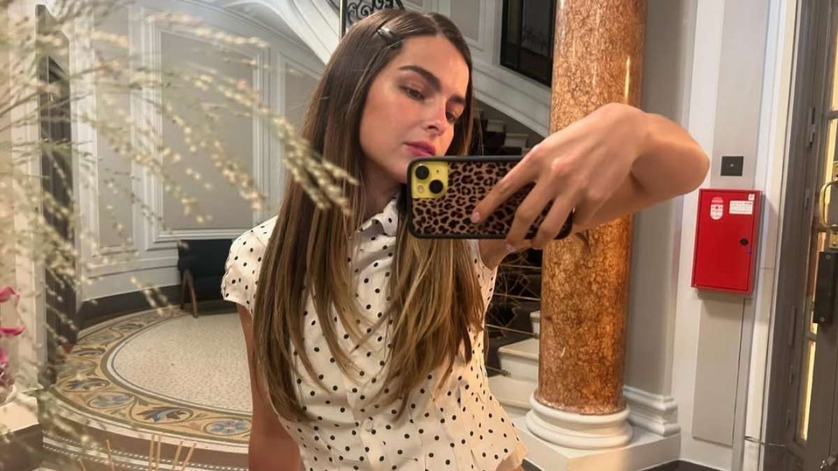 Addison Rae lying on the beach in a light pink bikini