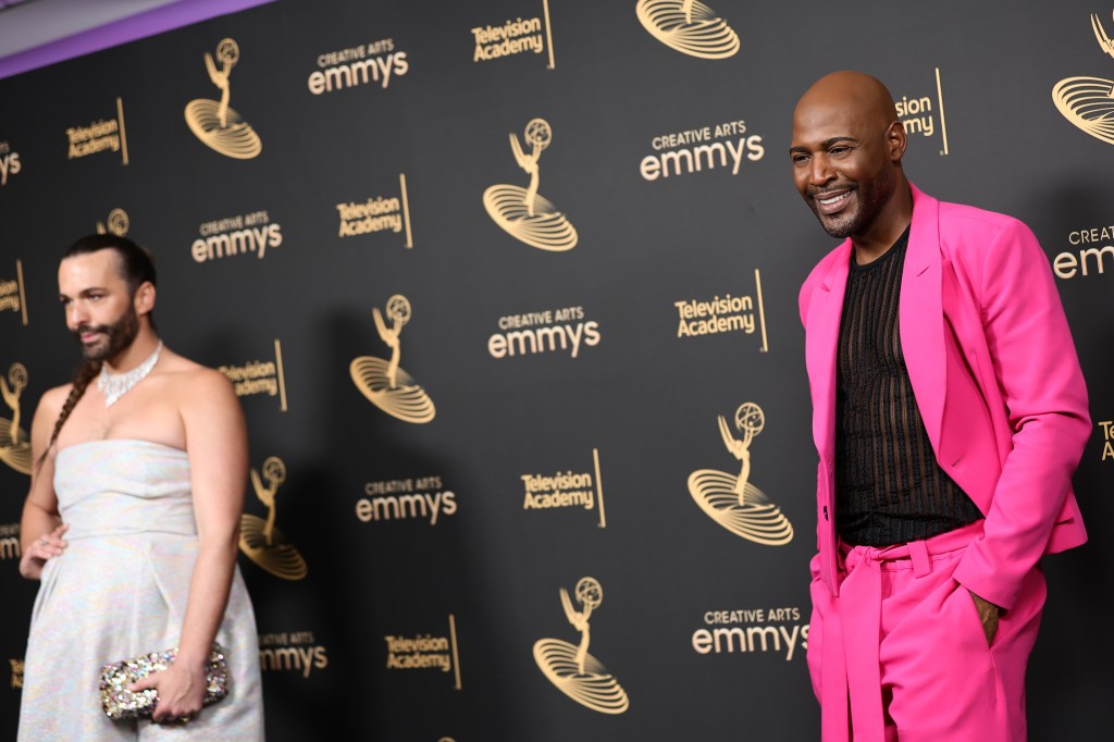 Karamo Brown in a pink suit, standing several feet away from Jonathan Van Ness at the Emmys