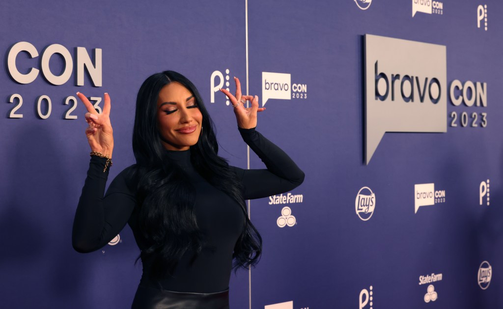 Monica Garcia at BravoCon 2023, wearing a black dress and holding up two peace signs