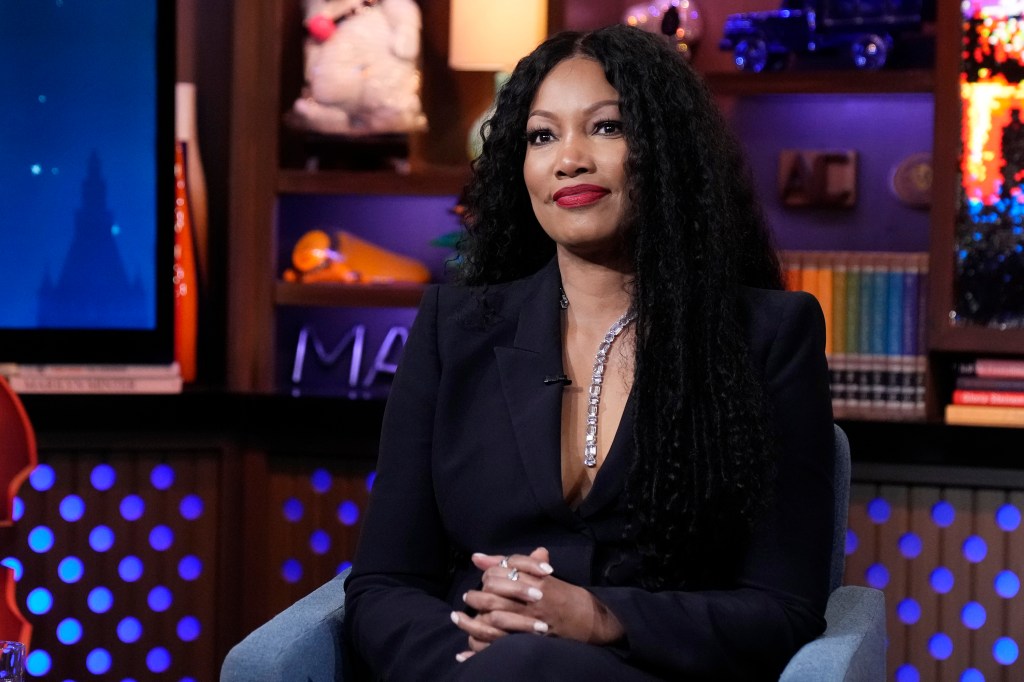 Garcelle Beauvais, sitting with her hands folded and wearing a black dress on Watch What Happens Live