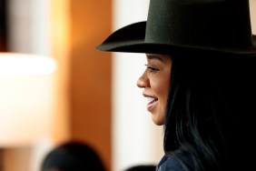 Angel Massie looking off to the side in a black cowboy hat and denim jumper