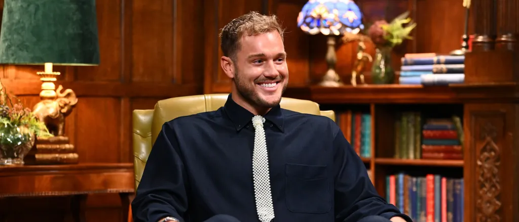 Colton Underwood in a black shirt and tie on The Traitors Season 4