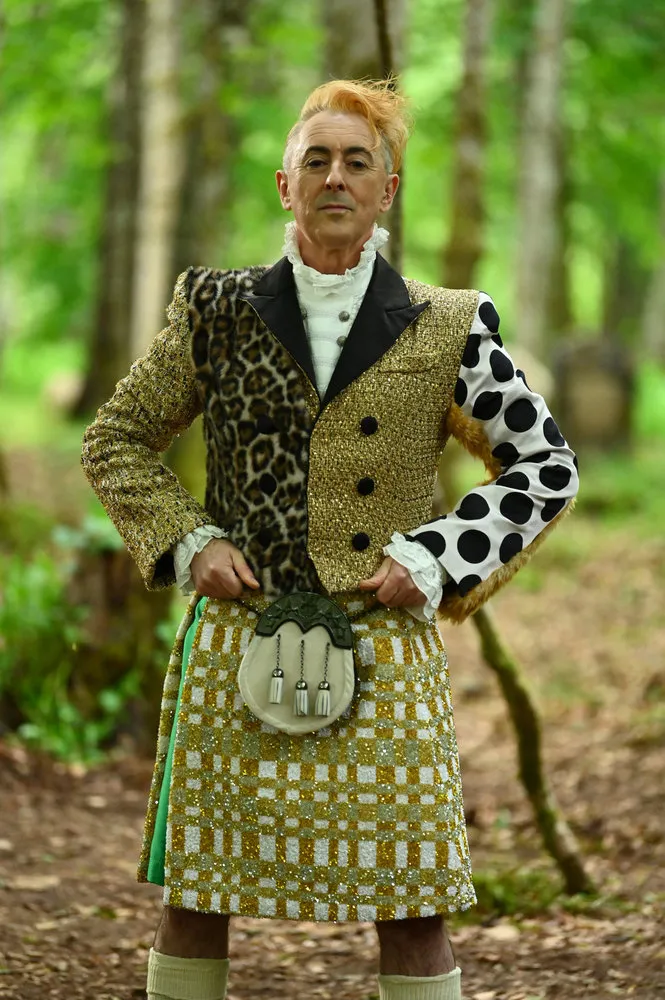 Alan Cumming in a golden kilt with a multi-patterned jacket