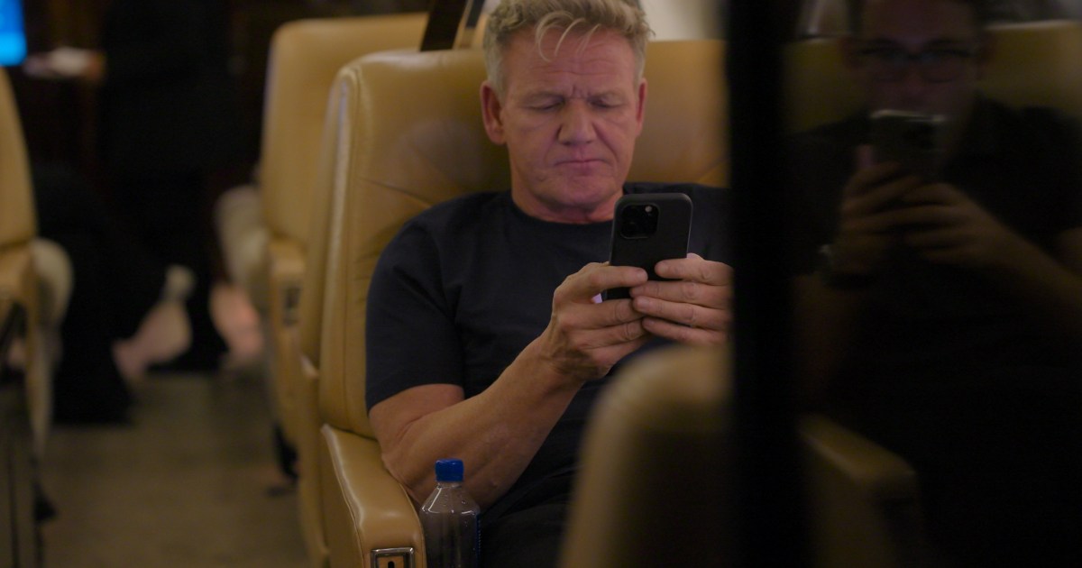Gordon Ramsay on an airplane looking at his phone