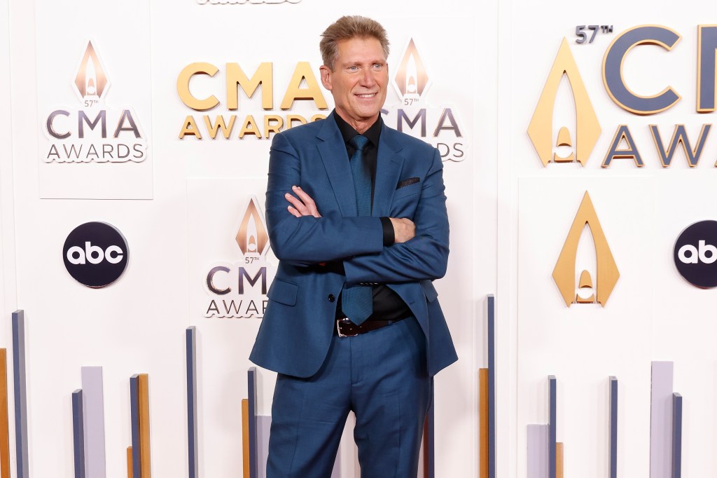 Gerry Turner in a blue suit with his arms crossed attending the CMA Awards