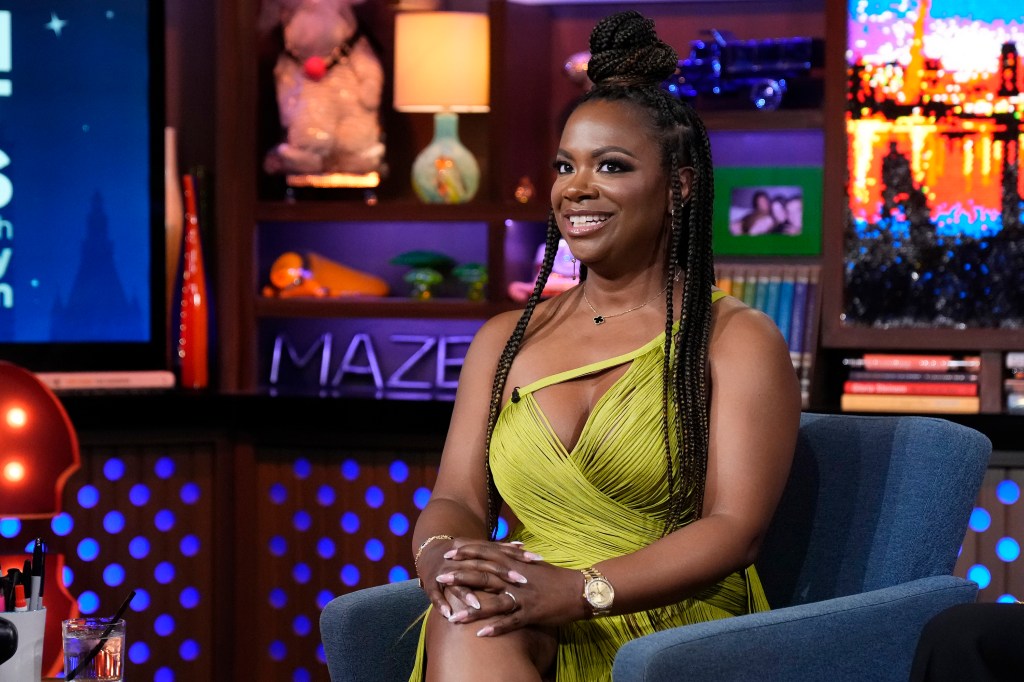Kandi Burruss in a yellow dress making a surprised expression on Watch What Happens Live