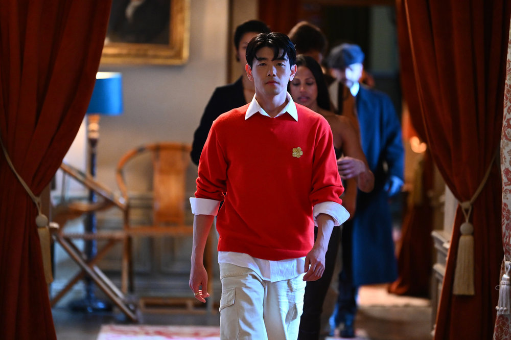 Eric Nam in a red shirt walking down a hallway in The Traitors Season 4