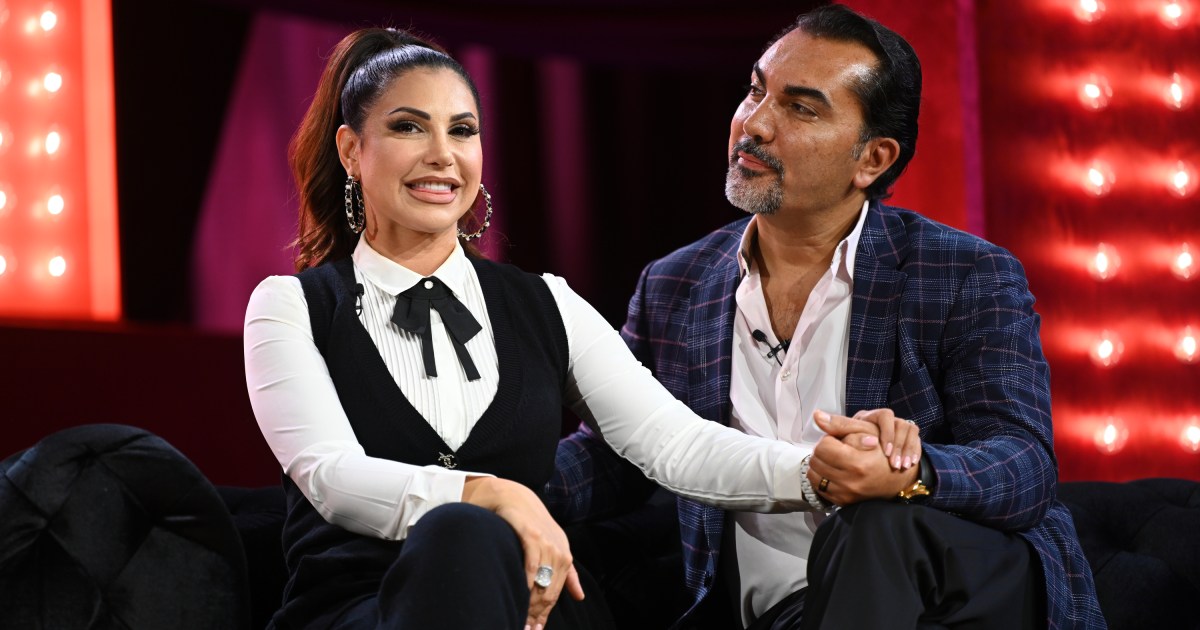 Jennifer and Bill Aydin holding hands on stage at BravoCon