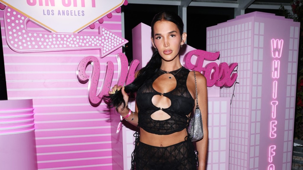 Lilah Gibney in a black top posing in front of pink White Fox signs