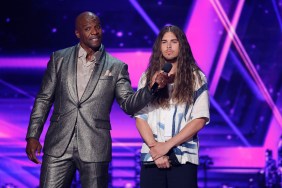Terry Crews in a silver suit holding up a microphone to Jourdan Blue