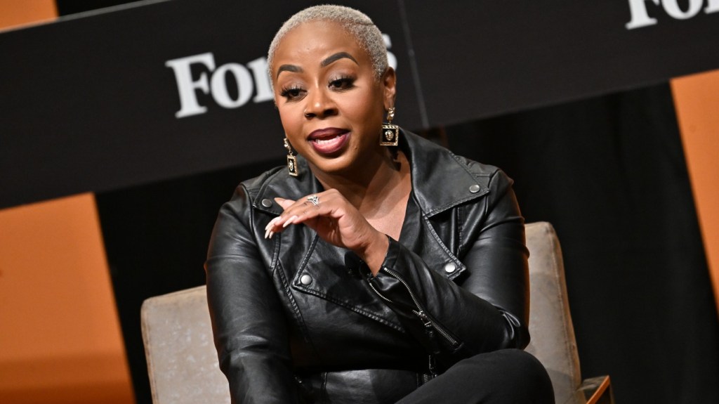 Pinky Cole in a black leather jacket speaking at Forbes event