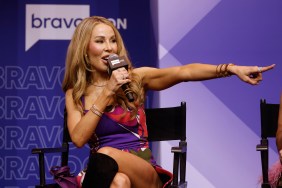 Lisa Hochstein on stage at BravoCon, holding a microphone and pointing her finger