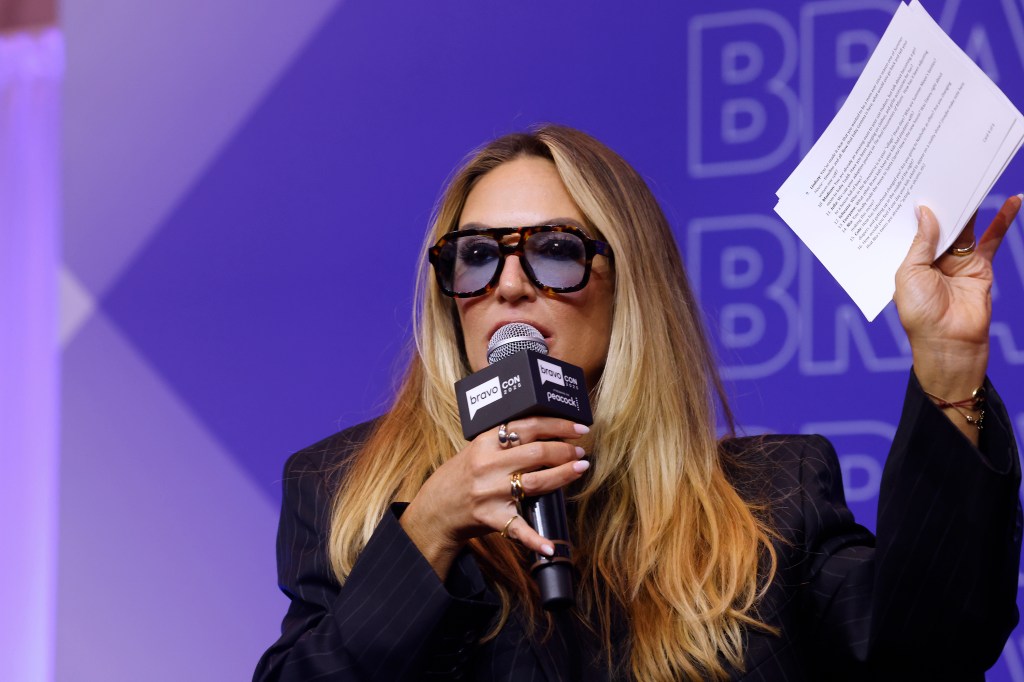 Kate Chastain talking into a microphone and holding up a note card