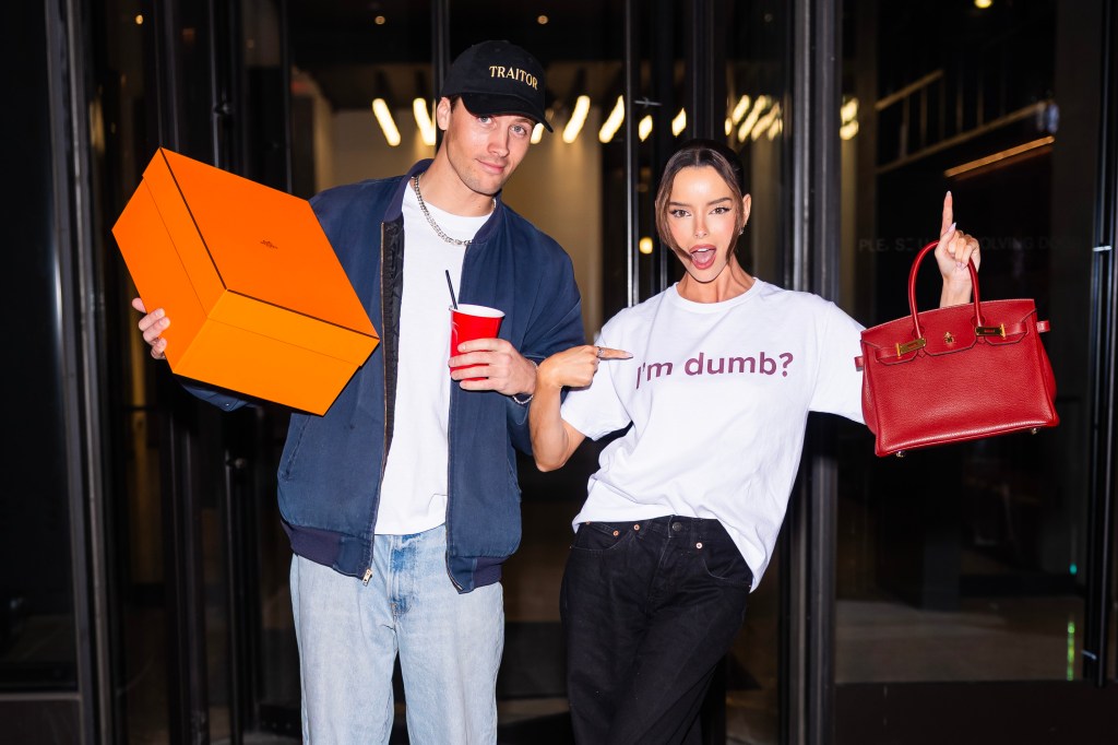 Rob Rausch and Maura Higgins walking out of Watch What Happens Live with an Hermés bag, Maura's shirt says, I'm dumb?"