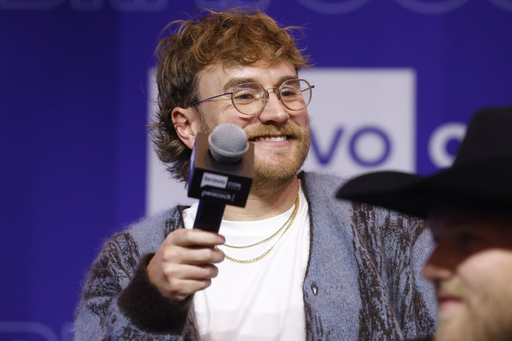 West Wilson at BravoCon 2025 holding a microphone and wearing a blue sweater