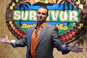 Benjamin Coach Wade with his arms out in front of the Survivor logo