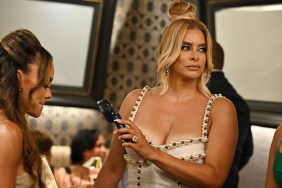 Robyn Dixon in a white dress, pointing a handheld fan at Ashley Darby