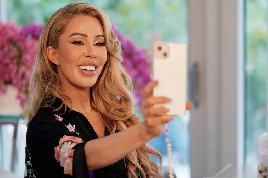 Lisa Hochstein holding her phone out and grinning